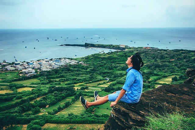 Joyfully sitting on a cliff's edge overlooking a seaside village